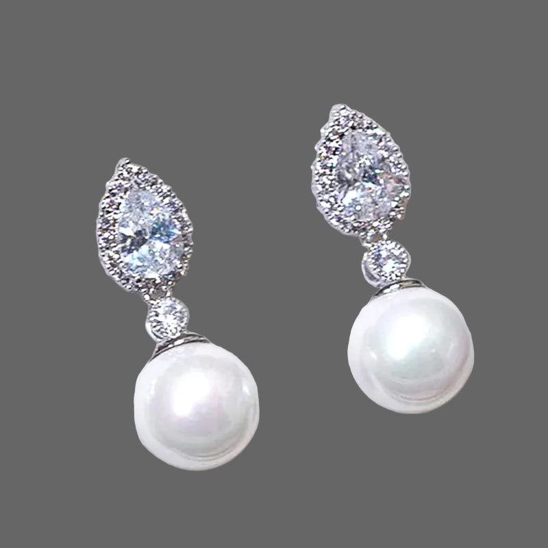 Boucles d'oreilles élégantes en perles d'imitation en forme de fleur, ornées de pierres CZ étincelantes. Un accessoire luxueux et féminin, parfait pour les mariages, les fêtes et les occasions spéciales.